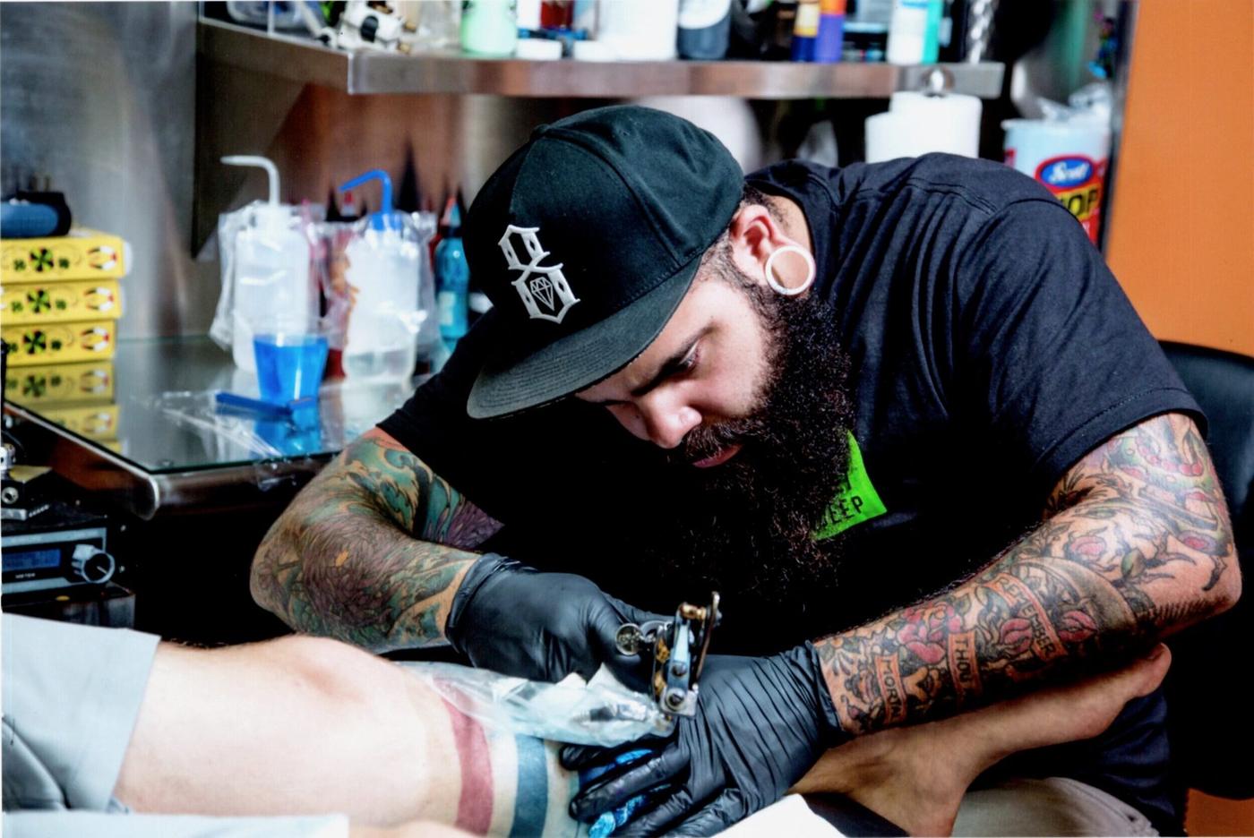 Chris Tate tattooing at Encore, working on a client's lower leg